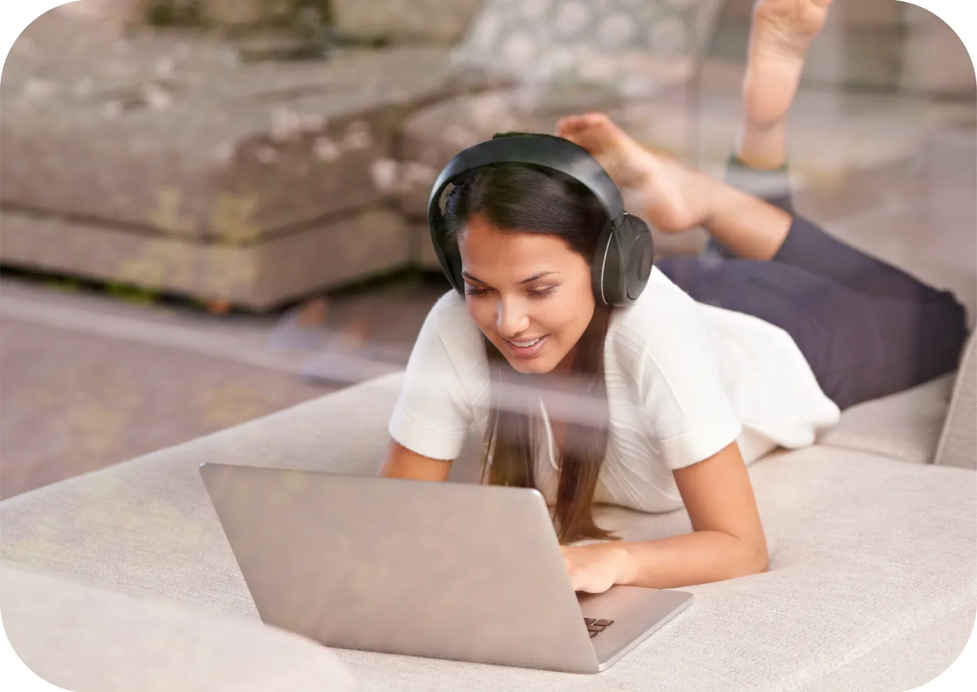 Mujer con audífonos usando su laptop en el sofá