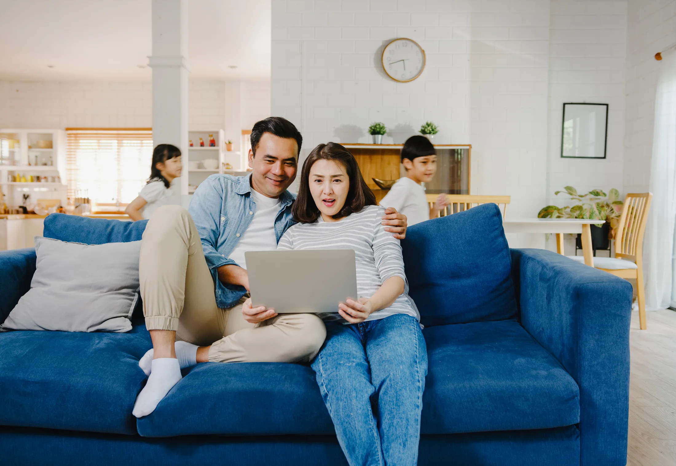 Pareja y sus hijos en un hogar moderno en Estados Unidos reaccionan con asombro a una laptop. Este es un gran ejemplo visual del tipo de internet residencial con alta velocidad y Wi-Fi robusto que las familias latinas en Estados Unidos necesitan para sus hogares conectados.