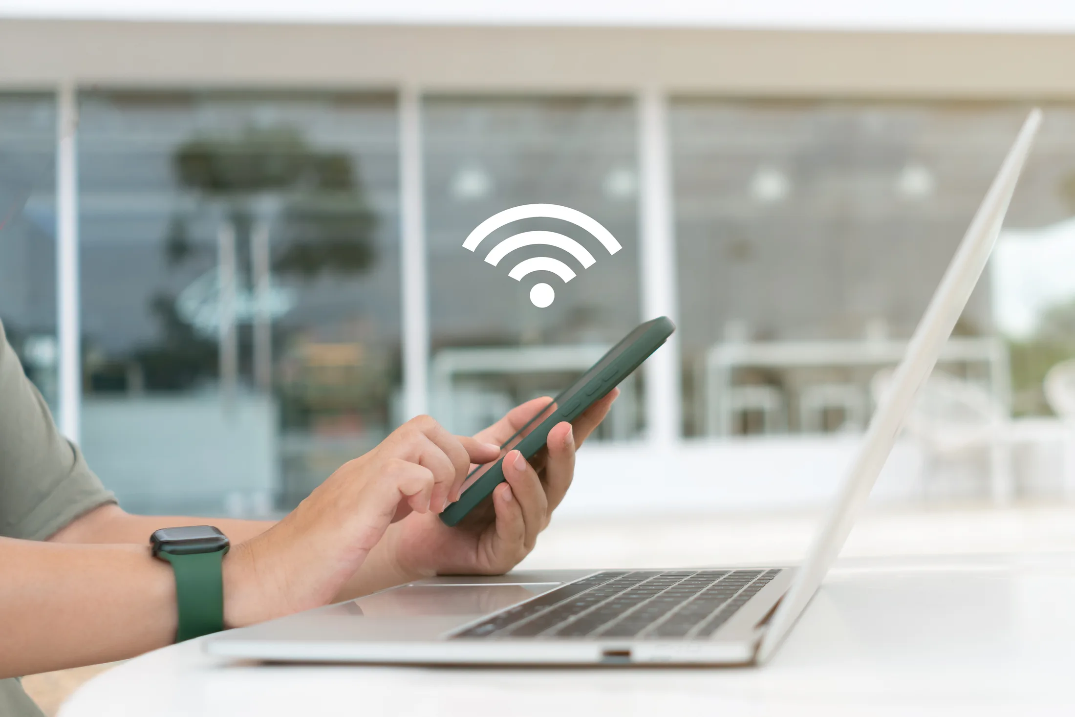 Mobile hotspot: Manos configurando una red Wi-Fi en un smartphone para compartir internet de alta velocidad a una laptop.