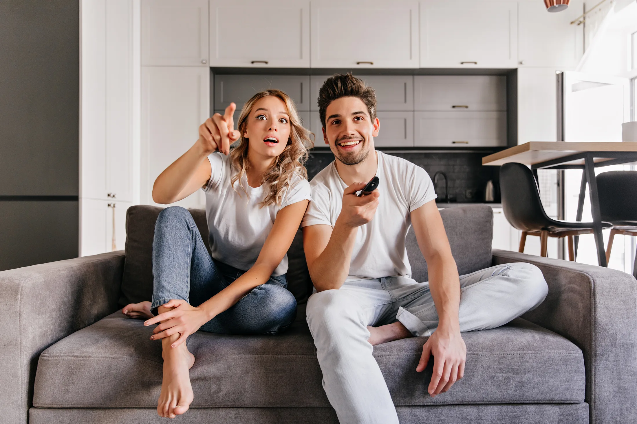 Streaming sin lag: Pareja emocionada viendo una película online en su Smart TV con internet de alta velocidad.