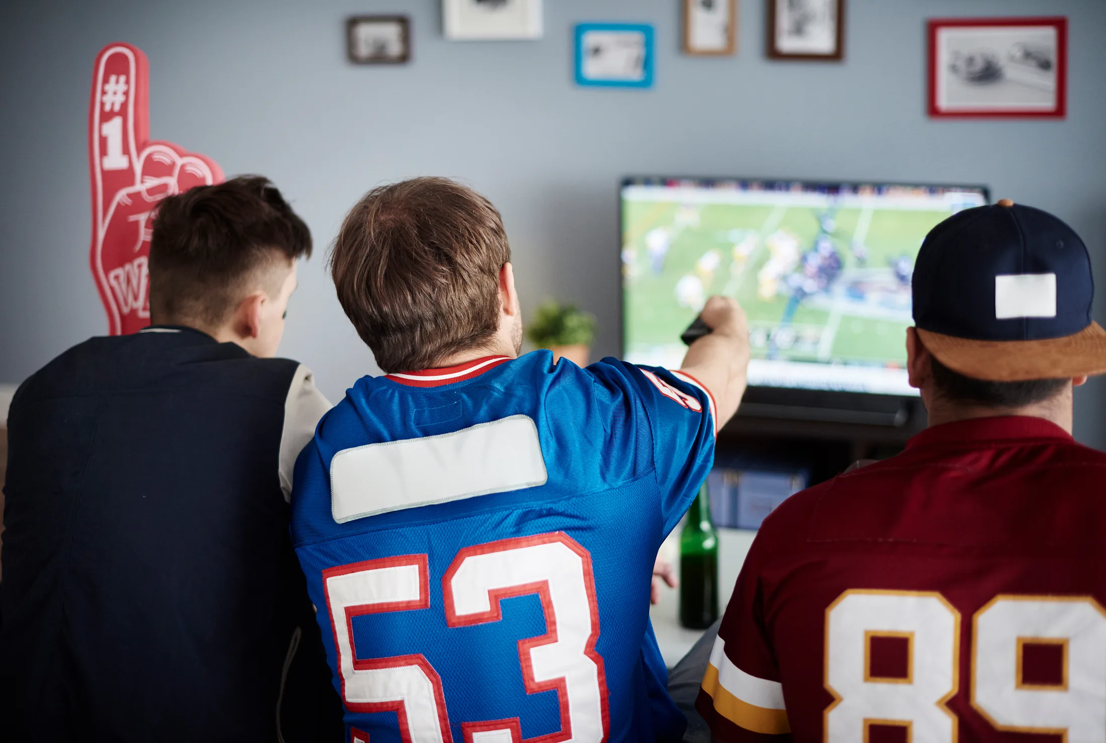 Live streaming sin lag: Grupo de amigos viendo un partido deportivo online en su Smart TV con internet de alta velocidad.