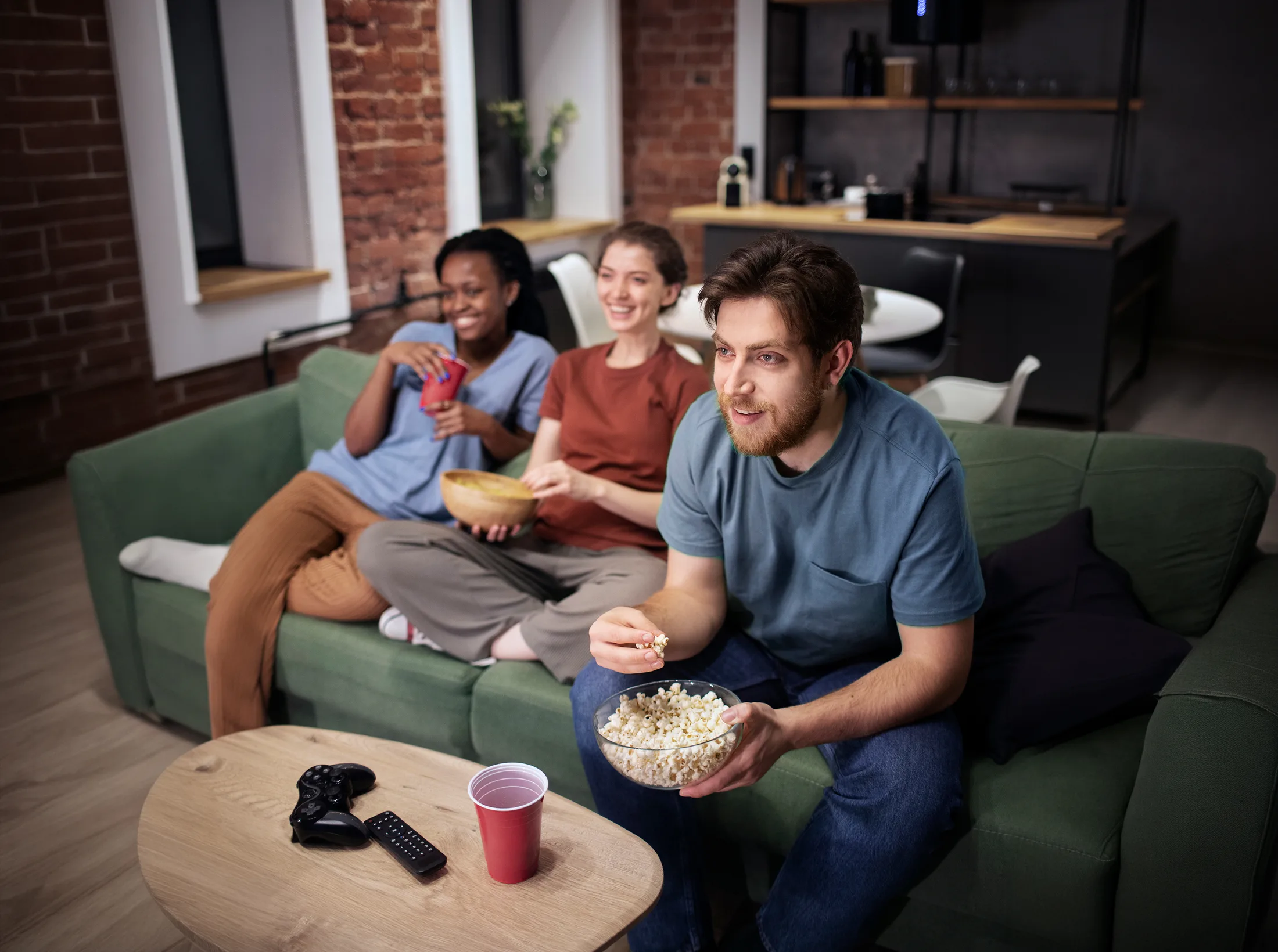 Streaming en casa: Grupo de amigos comiendo palomitas mientras disfrutan de una película online con internet de alta velocidad.