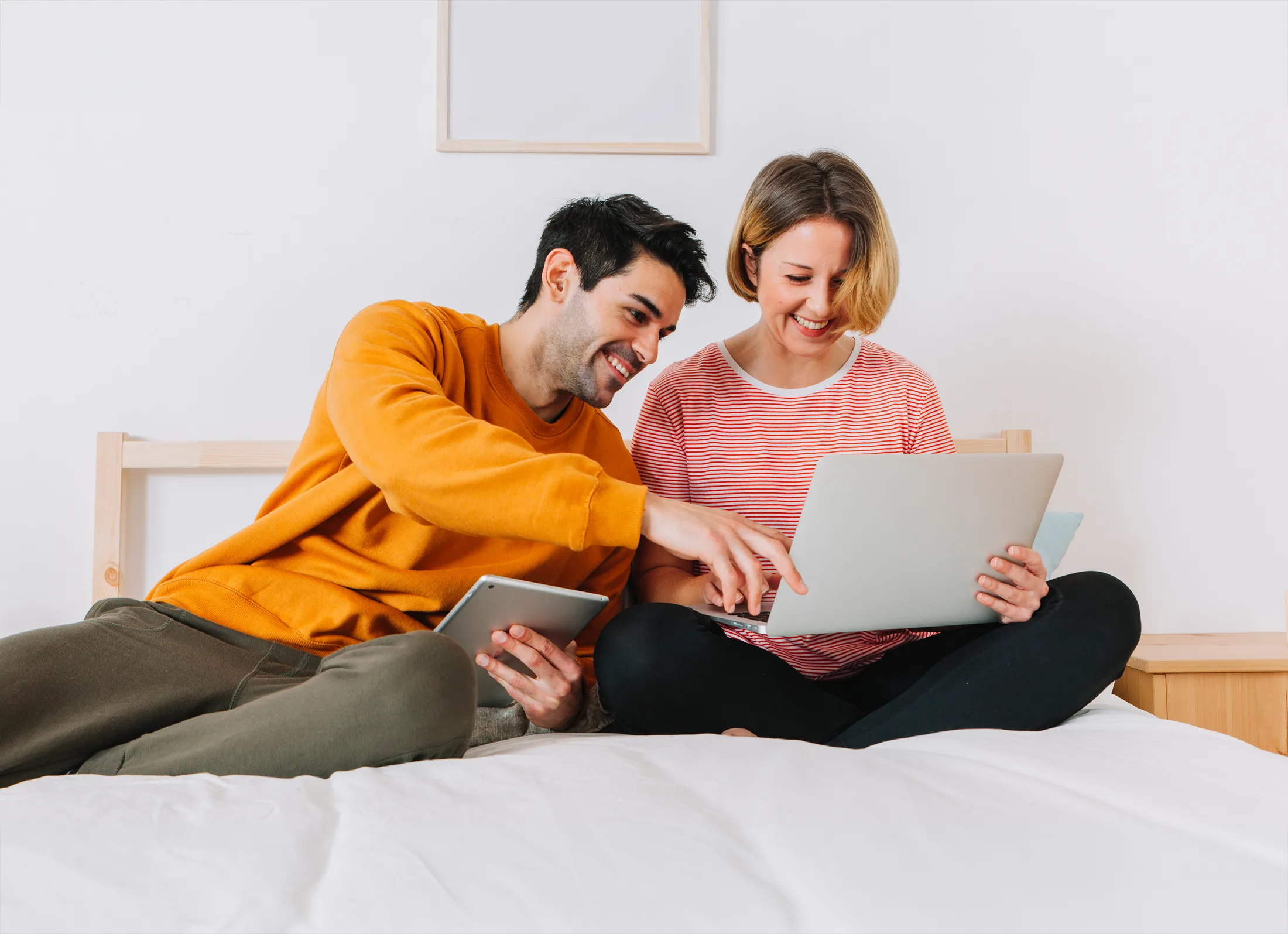 Conexión multidispositivo: Pareja feliz usando una laptop y una tablet al mismo tiempo con Wi-Fi rápido.
