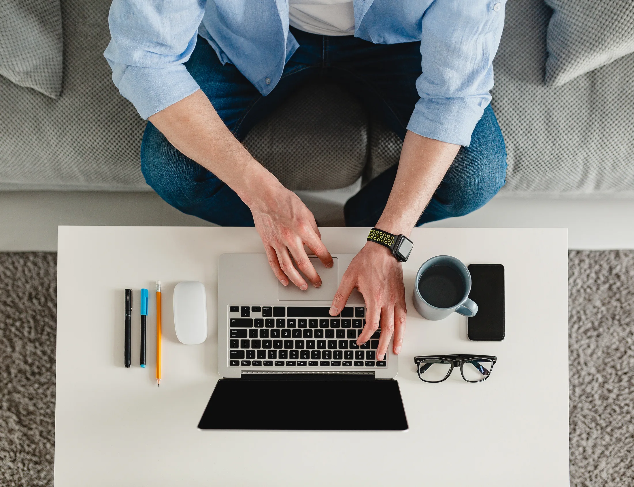 Work from home: Vista superior de una persona trabajando productivamente en su laptop desde el sofá.