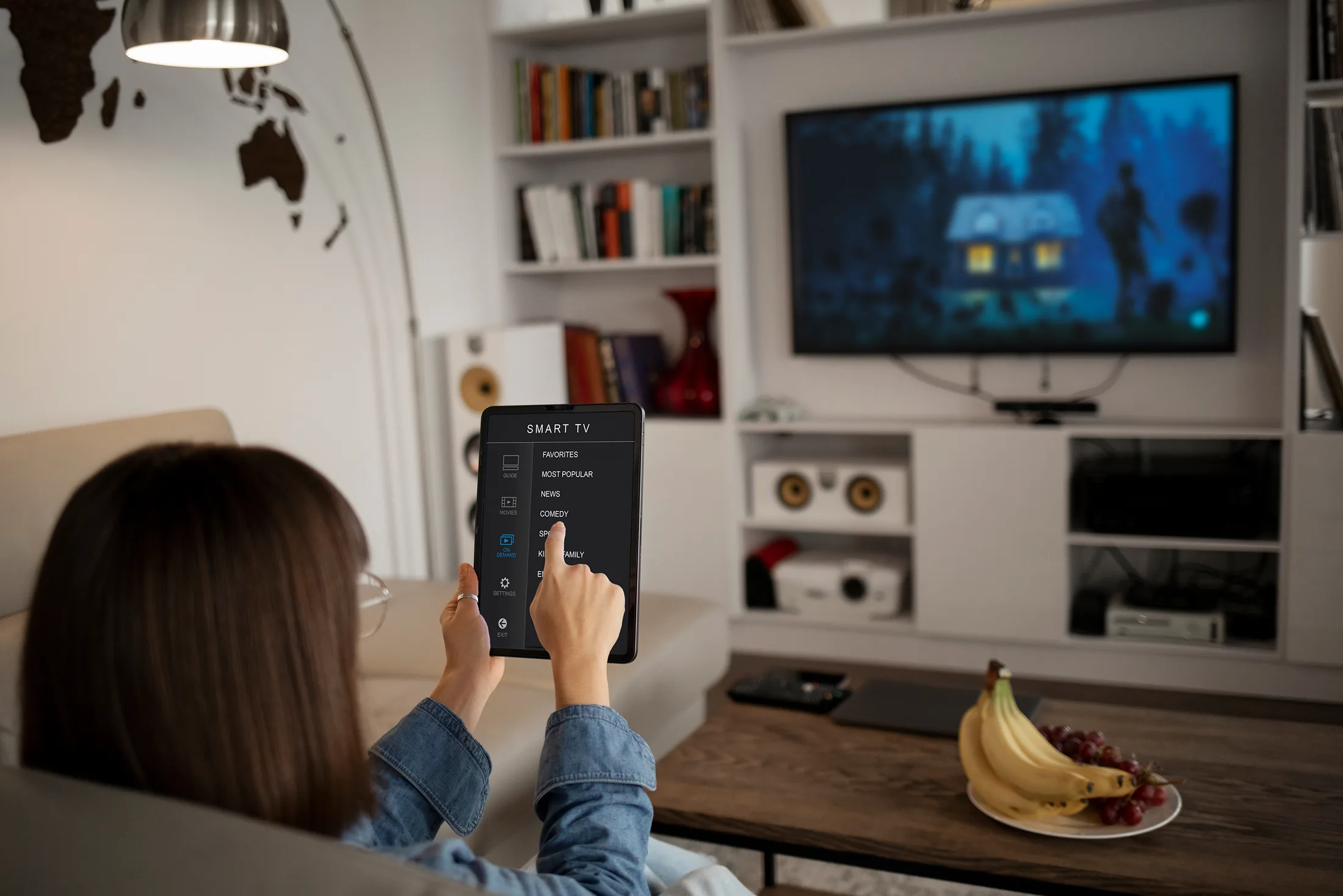 Smart home setup: Mujer usando una app en su tablet para controlar el streaming de su Smart TV por Wi-Fi.